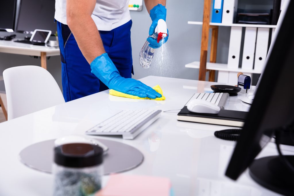 janitor cleaning white desk in office
